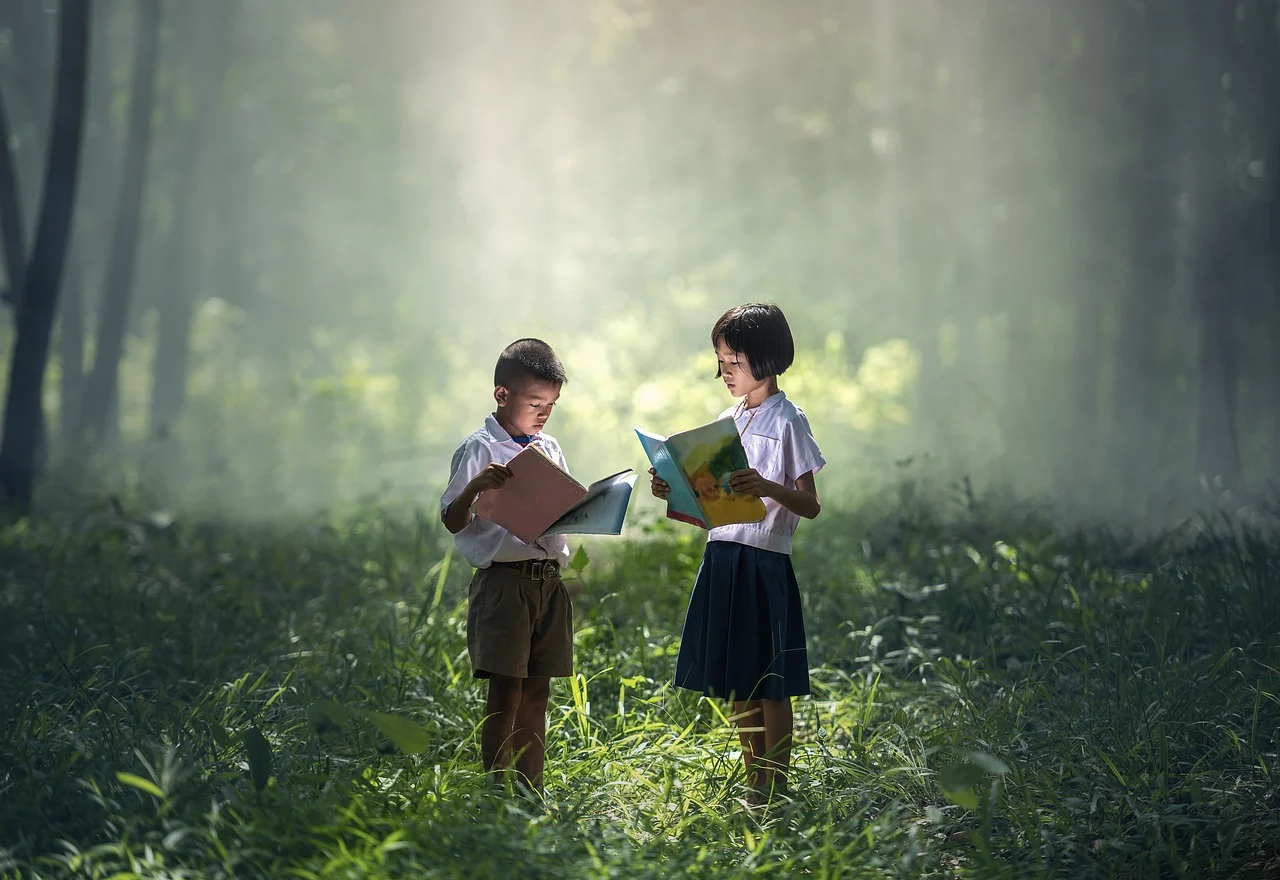 햇빛이 비치는 숲 속에서 책을 들고 서있는 한 소년과 소녀